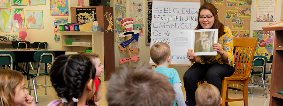 A student teacher reading to elementary students