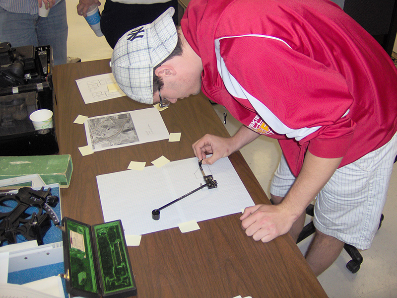 A student uses a polar planimeter to measure the area of a region by tracing its boundary.